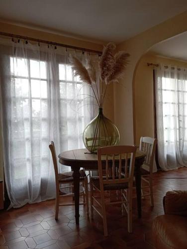 - une table à manger avec des chaises et un vase au-dessus dans l'établissement Le logis de Thaïs, à Henrichemont