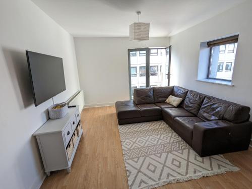 a living room with a leather couch and a flat screen tv at Best Location in Belfast! Free parking in Belfast