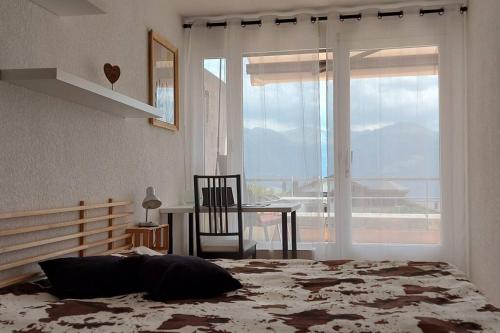a bedroom with a bed and a table and a window at Charmant logement vue dégagée Jeanne d'Arc in Crans-Montana
