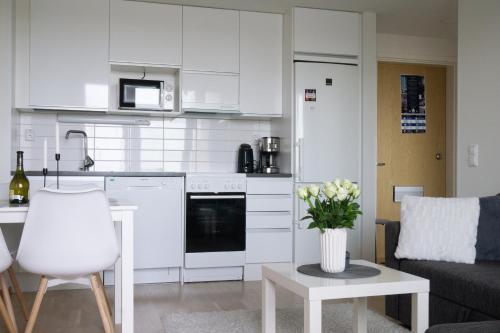 a kitchen with white cabinets and a table with a vase of flowers at Lovely 2R apartment in Oulu
