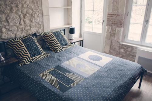 Bett mit blauer Bettdecke und Kissen darauf in der Unterkunft Les Belles Pierres - HyperCentre in Amboise