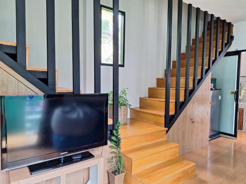 a living room with a tv and a staircase at Lipe Sunrise Beach House in Ko Lipe