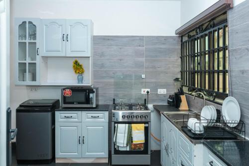 a kitchen with white cabinets and a stove top oven at Richie's Appartments in Accra