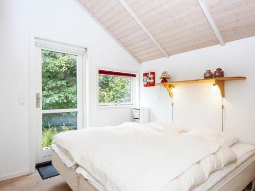 a white bedroom with a large bed and a window at Three-Bedroom Holiday home in Allingåbro 3 in Nørager