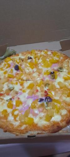 a pizza with different toppings on a box at las laureles de las americas in Huánuco