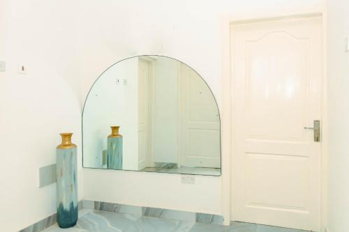 a mirror in a white room with two vases at Richie's Appartments in Accra