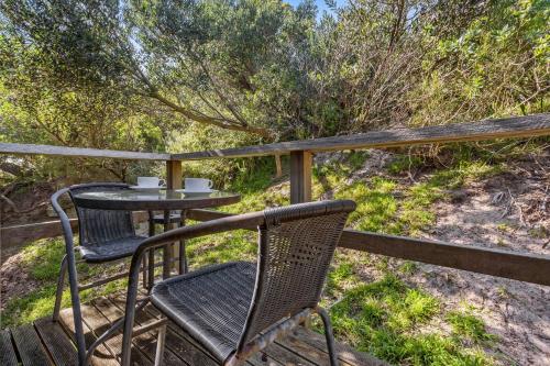 two chairs and a table on a wooden deck at Treetops Haven Venus Bay in Venus Bay