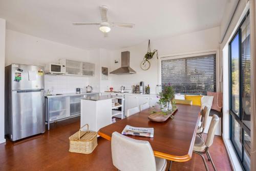 a kitchen with a wooden table and a dining room at Treetops Haven Venus Bay in Venus Bay