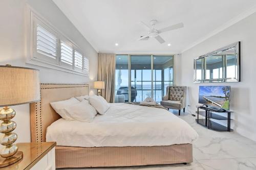 a bedroom with a bed and a chair and windows at Royal Retreat Peaceful Lakefront in Lake Munmorah