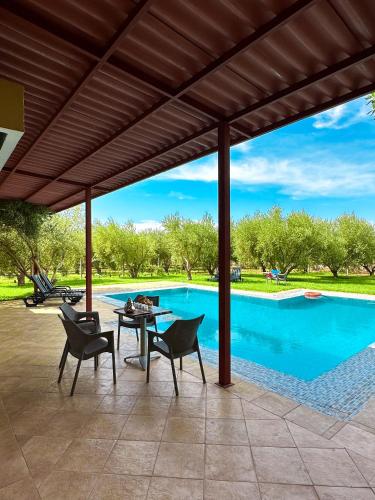 eine Terrasse mit einem Tisch, Stühlen und einem Pool in der Unterkunft Villa White dreams in Marrakesch