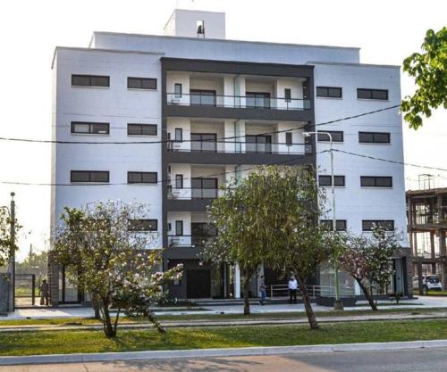 un edificio bianco con alberi di fronte di DEPARTAMENTo EN COMPLEJO RESIDENCIAL CON COCHERA a Resistencia