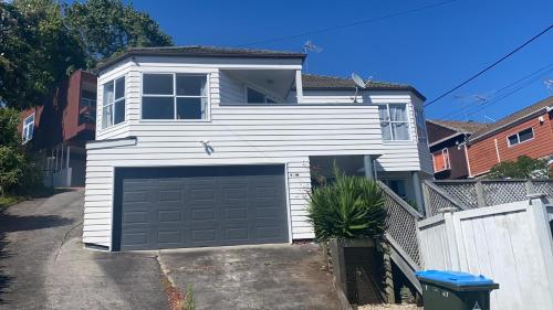 een wit huis met een garage op een oprit bij A private Large master room with en-suite in Auckland