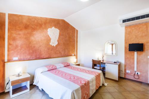a hotel room with a bed and a desk at Hotel Petri Marini in Aglientu