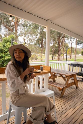 a woman sitting on a chair on a deck at Eight Acres Lakes Entrance in Lakes Entrance