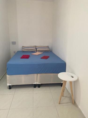 a bed with blue sheets and a table in a room at Flatsuico in Fortim