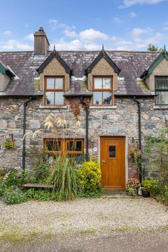 an old stone house with a wooden door at Priest Bridge Cottage in Bryansford