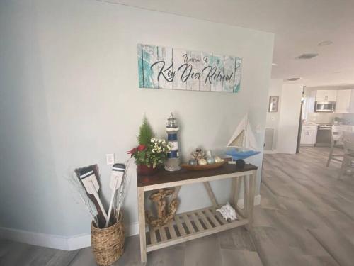 a living room with a table and a sign on the wall at key Deer Retreat/direct gulf access/hot tub in Big Pine Key