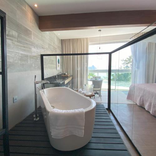 a bathroom with a bath tub and a bedroom at Rio Holiday Boutique Hotel in Niterói