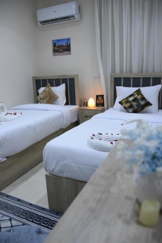 a hotel room with two beds and a table at Locanda Pyramids Hotel in Cairo