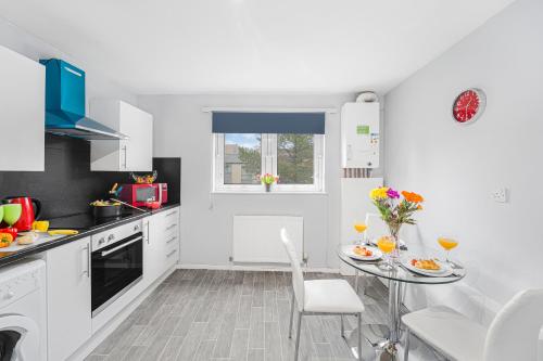 a white kitchen with a table and chairs in it at Premier - Maryhill Apartment in Glasgow