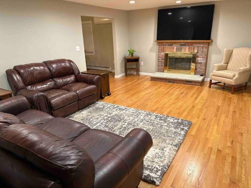 sala de estar con sofá de cuero y chimenea en Room in Single Family House - Suburban Neighborhood in Boston, en Boston