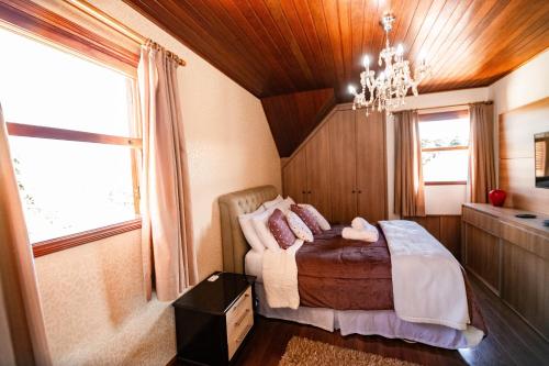 een slaapkamer met een bed en een kroonluchter bij Luxuoso duplex no Capivari in Campos do Jordão