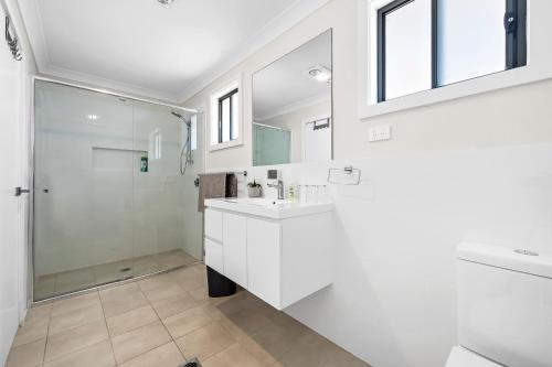 a white bathroom with a shower and a sink at 8Beds l 4 Suites with Office l Austral5 in Austral