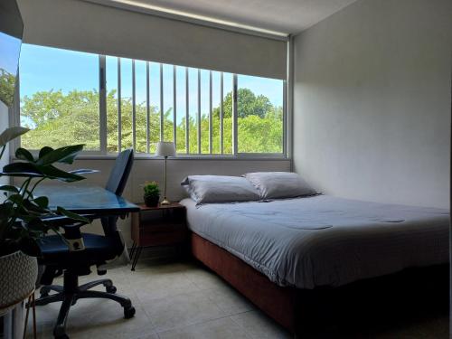 a bedroom with a bed and a desk and a window at Moderna y confortable habitación in Floridablanca