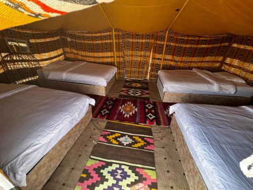 a room with three beds and a rug in a tent at Arab desert camp in Al Raka