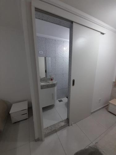uma casa de banho branca com um lavatório e um espelho em Apartamento Aconchegante em São Lourenço