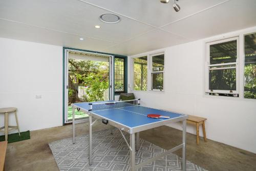 a blue ping pong table in a room with windows at Secret Garden Cottage Busselton in Busselton