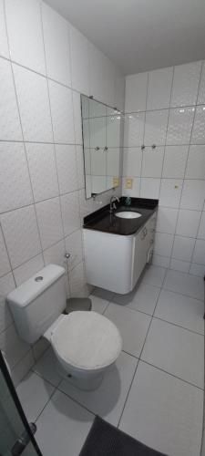 a white bathroom with a toilet and a sink at Apartamento aconchegante e bastante espaçoso in Natal