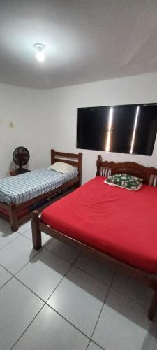 a bedroom with two beds with a red blanket at Apartamento aconchegante e bastante espaçoso in Natal