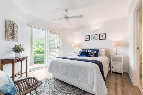 a white bedroom with a bed and a window at Quarterdeck in Noosaville
