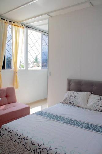 a bedroom with a bed and a chair and windows at Apartamento con la mejor ubicación Cali in Cali