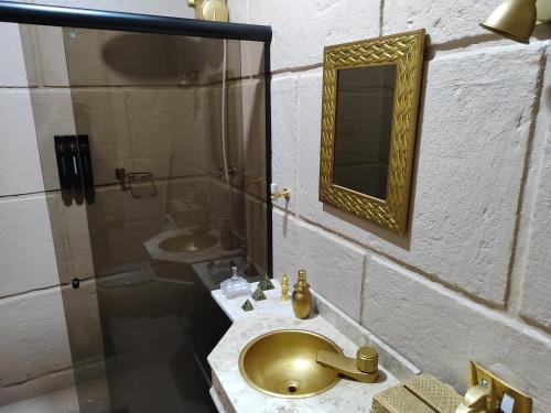 uma casa de banho com um lavatório dourado e um espelho em Pirâmide Quéops, Vila Mágica em Bueno Brandão