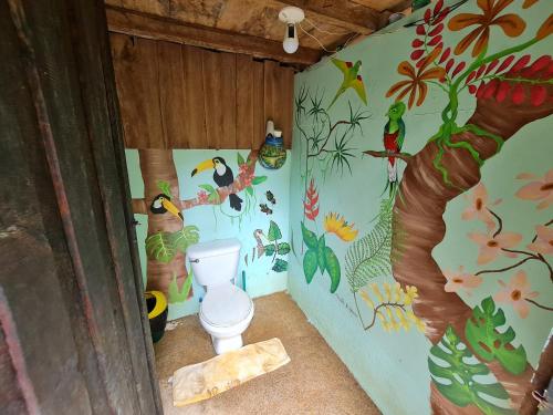 a bathroom with a toilet with birds and plants at Rio Agujitas Eco jungle - Island and Corcovado tours in Drake