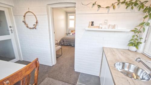 ein Bad mit einem Waschbecken und ein Zimmer mit einem Bett in der Unterkunft Cosy on Stirling in Oamaru
