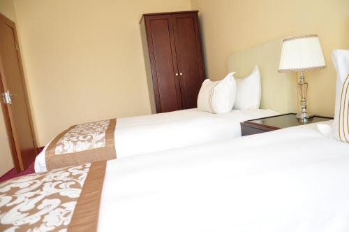 a hotel room with two beds and a lamp at Alpha Hotel Ulaanbaatar in Ulaanbaatar