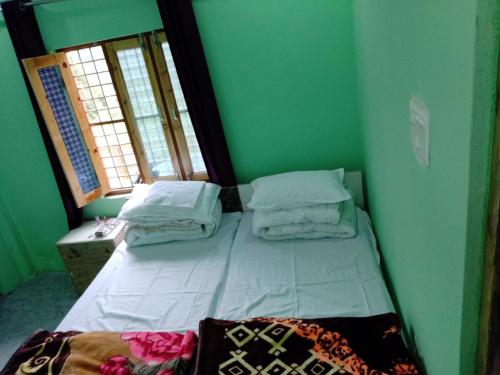 Cama pequeña en habitación verde con 2 ventanas en Shivashram, en Jyotirmath