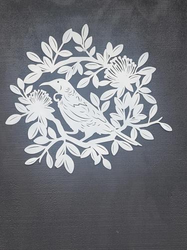 a white bird sitting on a branch of flowers at Tui Cottage in Rotowaro