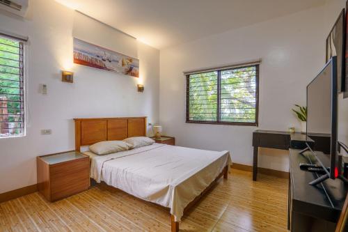 a bedroom with a bed and a flat screen tv at Oceanside 2 bedroom house, 50Mbps WiFi in Panglao Island