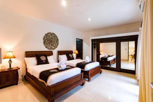 a bedroom with two beds and a large window at Sari Temuku Villa in Seminyak