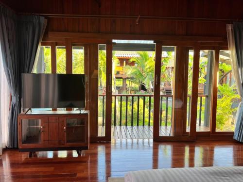 a living room with a flat screen tv on a cabinet at Bann Rai I Na in Phrae