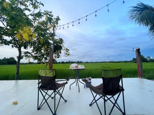 two chairs and a table on a patio at Bann Rai I Na in Phrae