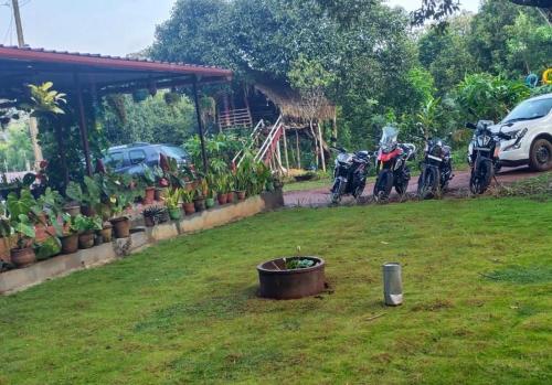 a group of motorcycles parked in a yard with a pot at Coorg Coffee Park Farmstay in Somvārpet