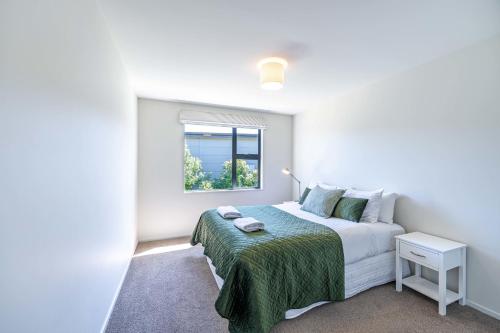 a white bedroom with a bed and a window at Hoheria Mountain Lodge in Wanaka