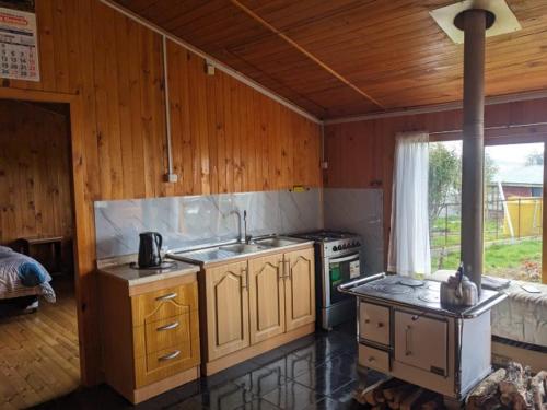 - une cuisine avec une cuisinière et un évier dans la chambre dans l'établissement Cabaña Coigües alberto vanz con vista al mar, à Quellón