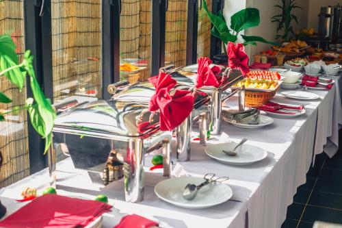 a long table with white plates and red flowers on it at Angkor Aurora in Siem Reap