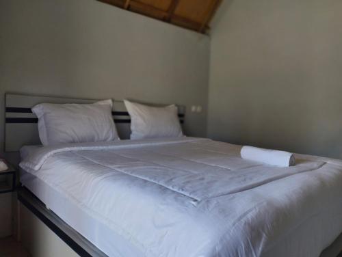 - un lit blanc avec des draps et des oreillers blancs dans l'établissement Sunset Point Kembang Kuning, à Tetebatu